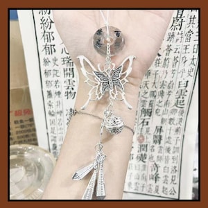 May include: A silver butterfly charm bracelet with a clear, round pendant and dangling decorative elements. The butterfly has detailed wings. The bracelet is shown against a backdrop of Chinese text.