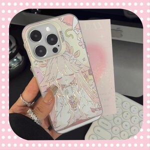 Może przedstawiać: Przezroczyste etui na telefon z r&oacute;żowo-białą ilustracją w stylu anime. Etui ma miękką, pastelową kolorystykę i przedstawia postać pijącą z kubka. Tekst "SO COOL" jest widoczny na etui.