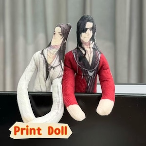May include: Two fabric print dolls. One doll is wearing a white outfit, and the other is wearing a red outfit with a black eye patch. The dolls have long arms and are standing next to each other. The text "Print Doll" is at the bottom.