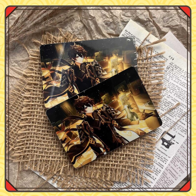 Może przedstawiać: Dwie prostokątne karty z ilustracją postaci z gry Genshin Impact. Karty przedstawiają postać z brązowymi włosami i czarno-złotym strojem. Tło zawiera złoty blask i elementy architektoniczne. Karty są umieszczone na powierzchni z juty.