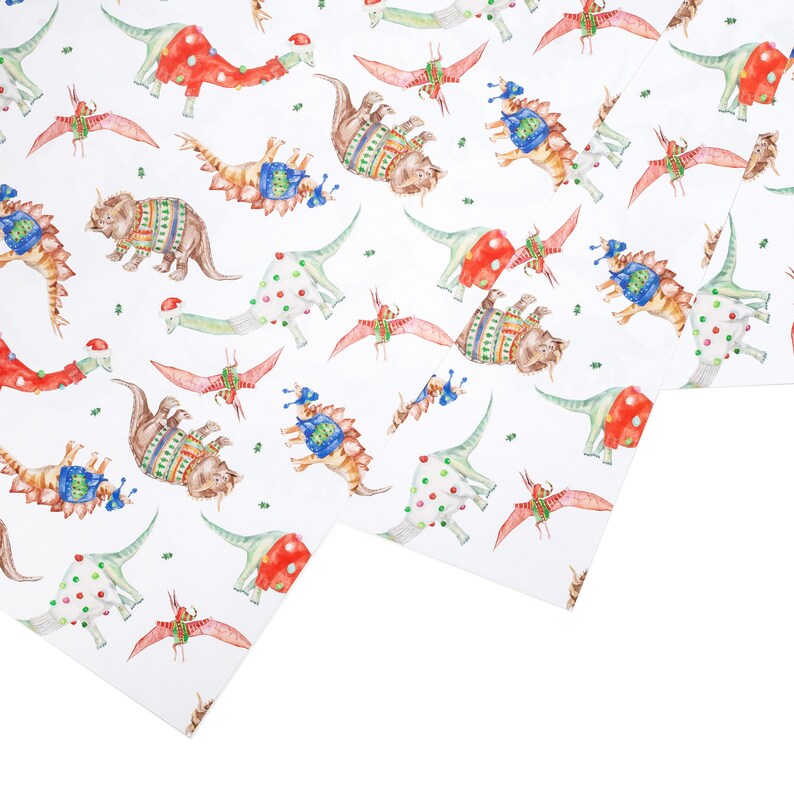 May include: White wrapping paper with a repeating pattern of dinosaurs wearing Christmas sweaters and hats. The dinosaurs are in various colors, including red, green, blue, and brown.