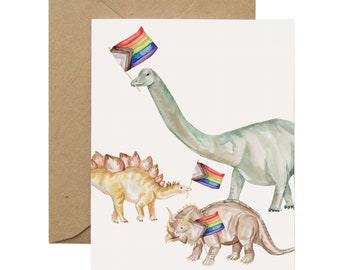 Könnte beinhalten: Eine Grußkarte mit einer Aquarell-Illustration von drei Dinosauriern, die Regenbogen-Pride-Flaggen halten. Die Dinosaurier sind ein grüner Brachiosaurus, ein brauner Stegosaurus und ein brauner Triceratops.