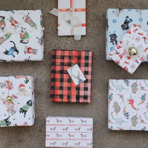 May include: Assortment of eight gift wrap designs featuring various animal patterns. The designs include cats wearing sweaters, dogs wearing sweaters, dachshunds, dinosaurs, and a plaid pattern.