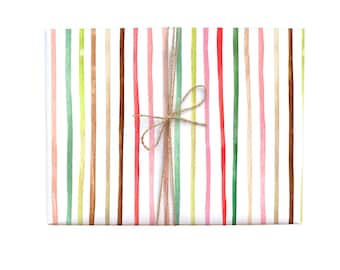 May include: White wrapping paper with colorful stripes in shades of pink, green, brown, and beige. The paper is tied with a brown twine bow.