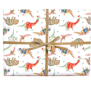 May include: White wrapping paper with a repeating pattern of dinosaurs wearing Christmas sweaters and hats. The dinosaurs are in shades of green, blue, red, and brown. The paper is tied with a brown ribbon and a gold bell.