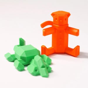 May include: A 3D printed orange teddy bear with a scarf and a 3D printed green alligator.