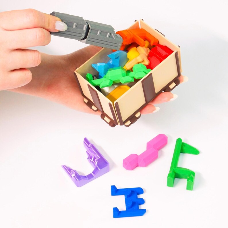 May include: A wooden toy train carriage filled with colourful plastic puzzle pieces. The pieces are in various shapes and sizes, and some are being placed into the carriage by a hand.