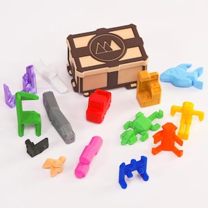 May include: A wooden box with a logo of three mountains on the lid, surrounded by a variety of colourful 3D printed figurines, including a car, a train, a shark, a giraffe, and several human figures.