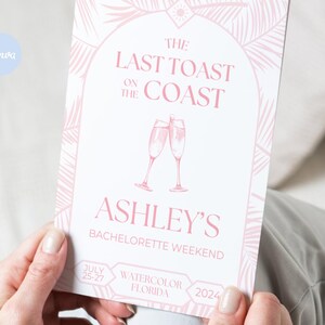 May include: A pink and white invitation with a tropical leaf design. The text reads "The Last Toast on the Coast Ashley's Bachelorette Weekend July 25-27 Watercolor Florida 2024".