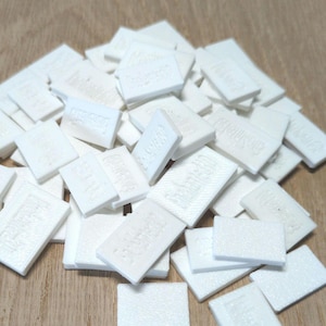 May include: A pile of white rectangular tiles with the word "remarkable" embossed on each tile.