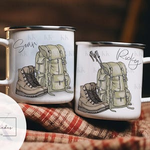 May include: Two white enamel mugs with silver rims, each featuring a hiking-themed design. One mug has the name "Sean" and the other "Ricky" in script. The designs include a backpack, hiking boots, and trekking poles.