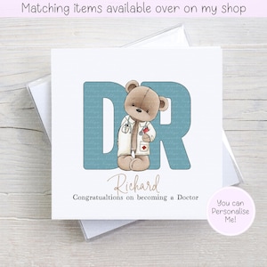 May include: A greeting card featuring a teddy bear dressed as a doctor, with the letters "DR" in teal. The card reads "Richard, Congratulations on becoming a Doctor." A small pink circle says "You can Personalise Me!"