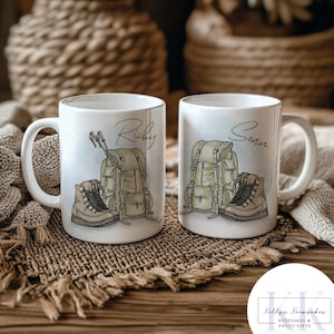 May include: Two white ceramic mugs with handles, each featuring a hiking-themed design. One mug has the name "Ricky" and the other "Sean" in script. The designs include a backpack, hiking boots, and trekking poles.
