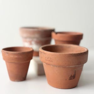 Puede incluir: Un juego de tres tazas de cerámica con un acabado moteado y mate. Las tazas son de color crema, gris claro y gris oscuro. Cada taza tiene un diseño simple y minimalista y un asa redondeada. Las tazas están apiladas.