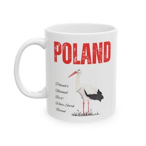 May include: White ceramic mug with a red "POLAND" graphic and a white stork illustration. The text below the stork reads "Poland's National Bird: White Stork 'Bocian'".
