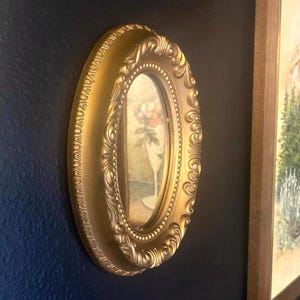 Petite oval mirror with gold gilded frame, vintage plastic ornate and detailed wall mirror