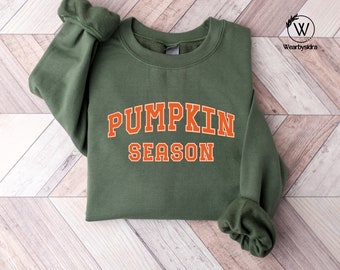 May include: A green sweatshirt with the text "Pumpkin Season" in orange letters.