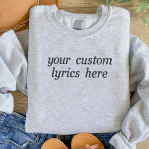May include: A grey sweatshirt with the text "your custom lyrics here" printed on the front.