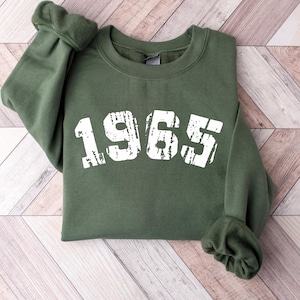 May include: A green sweatshirt with the year 1965 printed in white on the front.