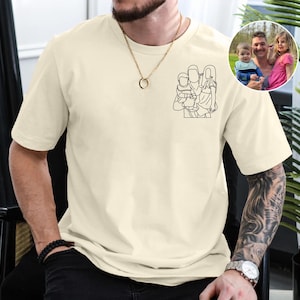 May include: A cream-coloured t-shirt with a black outline of a family of four. The outline is of a man holding a baby, a woman holding a child, and the two children.