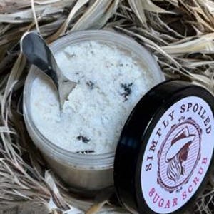 Peut inclure: Un gommage au sucre blanc dans un pot transparent avec un couvercle noir. Le couvercle porte une &eacute;tiquette rose et blanche avec le texte "Simply Spoiled Sugar Scrub".