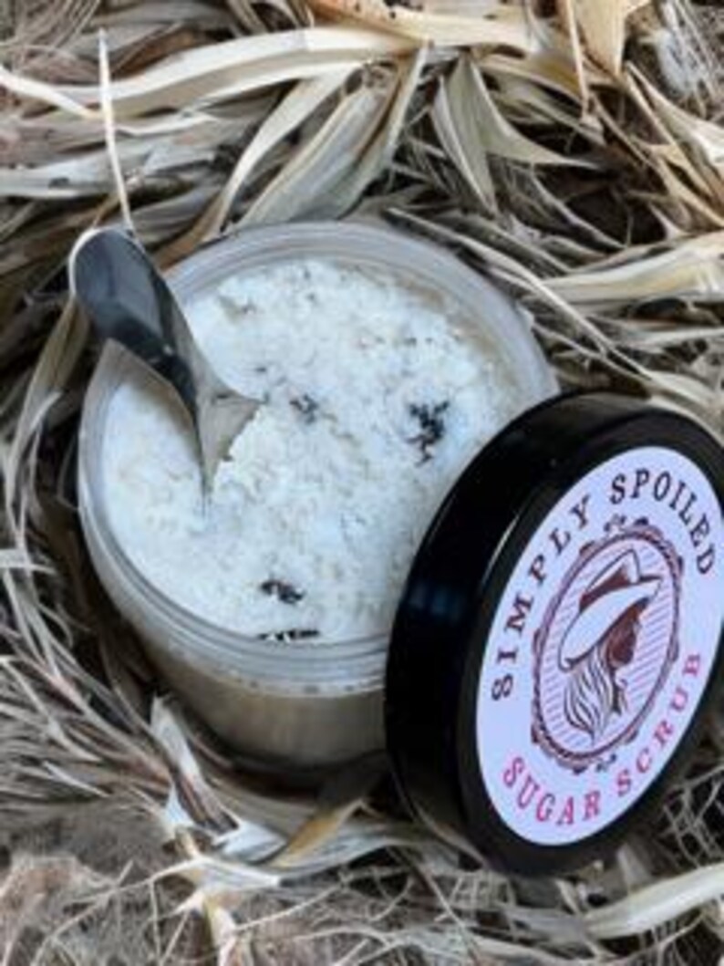 Peut inclure: Un gommage au sucre blanc dans un pot transparent avec un couvercle noir. Le couvercle porte une &eacute;tiquette rose et blanche avec le texte "Simply Spoiled Sugar Scrub".
