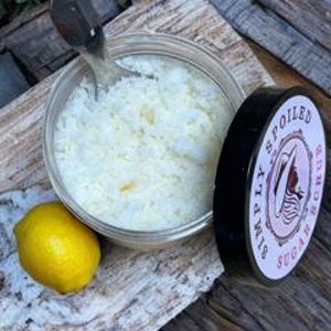 Peut inclure: Un pot en verre transparent rempli de sels de bain blancs, un citron et un couvercle noir avec le texte "Simply Spoiled" en lettres blanches.