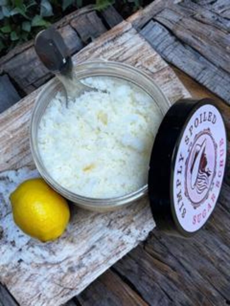Peut inclure: Un pot en verre transparent rempli de sels de bain blancs, un citron et un couvercle noir avec le texte "Simply Spoiled" en lettres blanches.