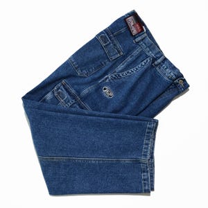 May include: Blue denim cargo pants with multiple pockets and a logo patch. The pants have a classic five-pocket design, a button and zipper closure, and a relaxed fit. The brand name "Plug" is visible on a tag.