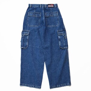 May include: Blue denim cargo pants with multiple pockets, including two large side pockets and two back pockets. The pants have a wide leg design and a "Rhino" label on the back. The denim is a medium wash.