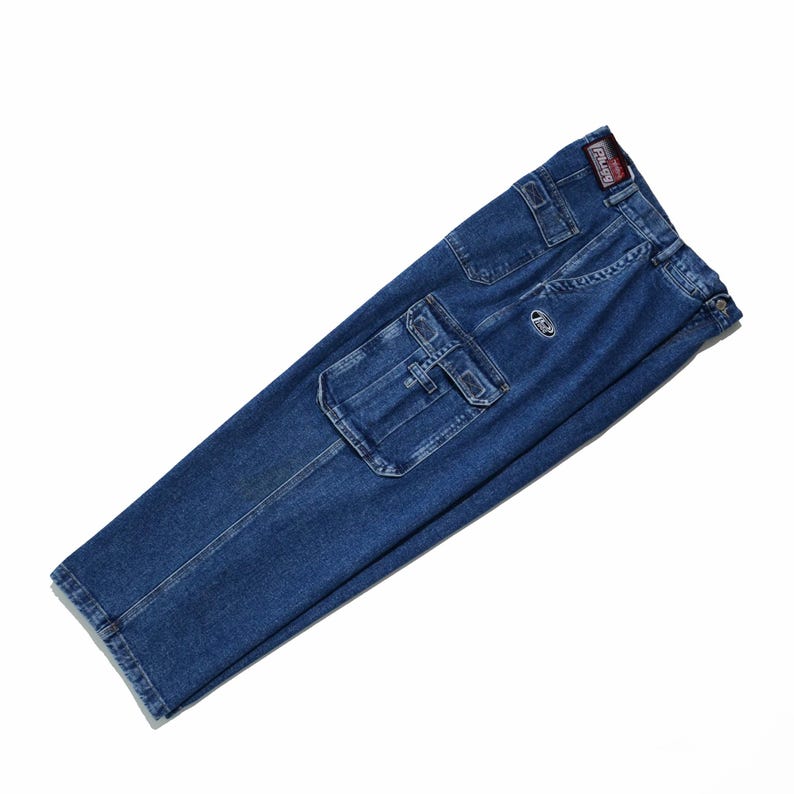 May include: Blue denim cargo pants with multiple pockets, including large side pockets. The pants have a straight leg design and a small logo patch near the front pocket. The brand label is visible on the back.