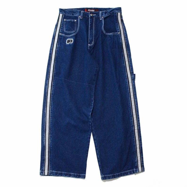 May include: Dark blue denim jeans with white and black side stripes. The jeans have a wide leg design, front pockets, and a small logo patch. The brand name "Plugge" is visible on the waistband.