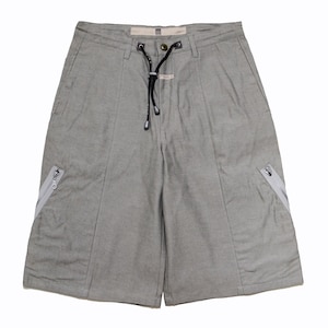 May include: Light gray shorts with a drawstring waist and two front pockets with zippers. The shorts have a tailored design with vertical seams and a small tag near the waist. The fabric appears to be a woven material.