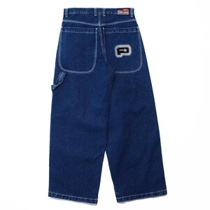 May include: Dark blue denim jeans with a wide leg design. Features include large back pockets, a small pocket on the front, and a logo patch on the back pocket. The jeans have white stitching and a button and zipper closure.