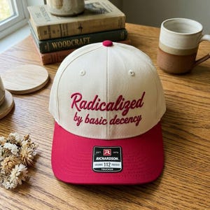 May include: A white ceramic mug with a black handle and the text "But First, Coffee" in a black, handwritten-style font. The mug is on a white surface.