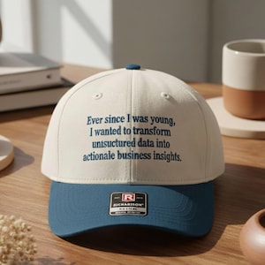 May include: A cream and blue baseball cap with the text: "Ever since I was young, I wanted to transform unstructured data into actionable business insights." The cap has a blue brim and a small blue button.
