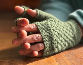 May include: A pair of green fingerless gloves with a textured knit pattern. The gloves are folded over the hands, with the fingertips exposed.