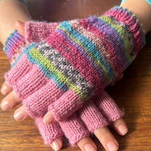 May include: Pink fingerless gloves with a colorful striped pattern on the back of the hand.