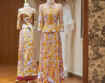 May include: A traditional Chinese wedding dress with a mandarin collar and long sleeves. The dress features intricate gold embroidery on a red and yellow background, with a matching skirt and a red fringe hem. The dress is displayed on a mannequin.