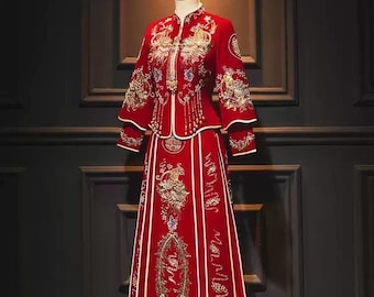 May include: A traditional Chinese wedding dress in red with gold embroidery and beaded accents. The dress features a long skirt and a fitted jacket with a mandarin collar.