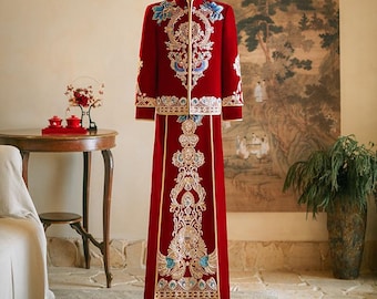 May include: A traditional Chinese wedding outfit in red with gold and blue embroidery. The outfit includes a long-sleeved jacket and a long skirt.