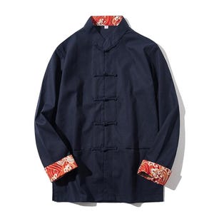 Può includere: Una camicia a maniche lunghe blu navy con colletto alla coreana e cinque bottoni. I polsini e il colletto sono foderati con un motivo floreale rosso e arancione.