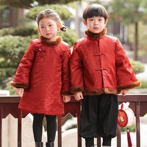 Peut inclure: Deux enfants portant des tenues chinoises traditionnelles rouges assorties. Les tenues comprennent des vestes avec des cols et des poignets en fourrure, et des pantalons noirs. La fille porte une robe, et le garçon porte une veste et un pantalon. Les tenues ont des motifs complexes.