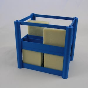 May include: A blue plastic soap drying rack with four compartments. The rack is filled with four bars of soap.