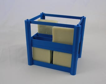 May include: A blue plastic soap drying rack with four compartments. The rack is filled with four bars of soap.