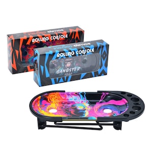 May include: A black rolling tray with a colorful design featuring a skull and flames. The tray has a metal stand and multiple compartments. The tray is packaged in a box with the words "Rolling Console" and "Gangster Trap" printed on it.