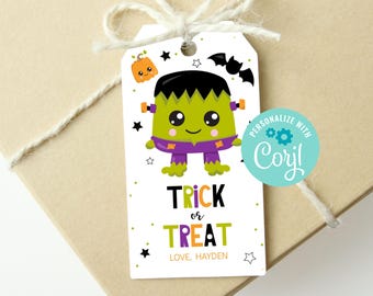 Op de afbeelding: Een witte Halloween-cadeaulabel met een cartoon Frankenstein-monster illustratie. Het label leest "Trick or Treat" in zwart en oranje, met een naam eronder. Een pompoen, vleermuis en sterren versieren het label.