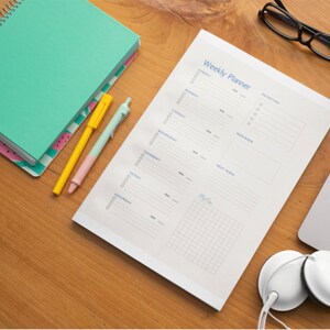 May include: A white weekly planner with a blue heading "Weekly Planner" and a gridded section at the bottom. The planner has sections for each day of the week, with space for notes and reminders.