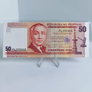 Puede incluir: Un billete de banco filipino de 50 pesos rojo y blanco con el texto "REPUBLIKA NG PILIPINAS" y "LIMAMPUNG PISO" impreso en él. El número de serie "FL205916" es visible en el billete.