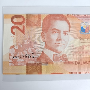 Puede incluir: Un billete filipino de veinte pesos con el retrato de un hombre con traje y pajarita. El billete tiene el texto "REPUBLIKA" y "DALAWA" impresos. El número de serie "WN747989" es visible.